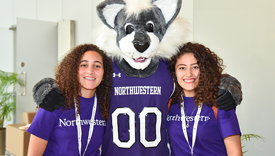 Two students standing with Willie Wildcat
